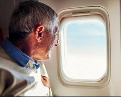 Adulto mayor observando a través de una ventana de avión - Volaris
